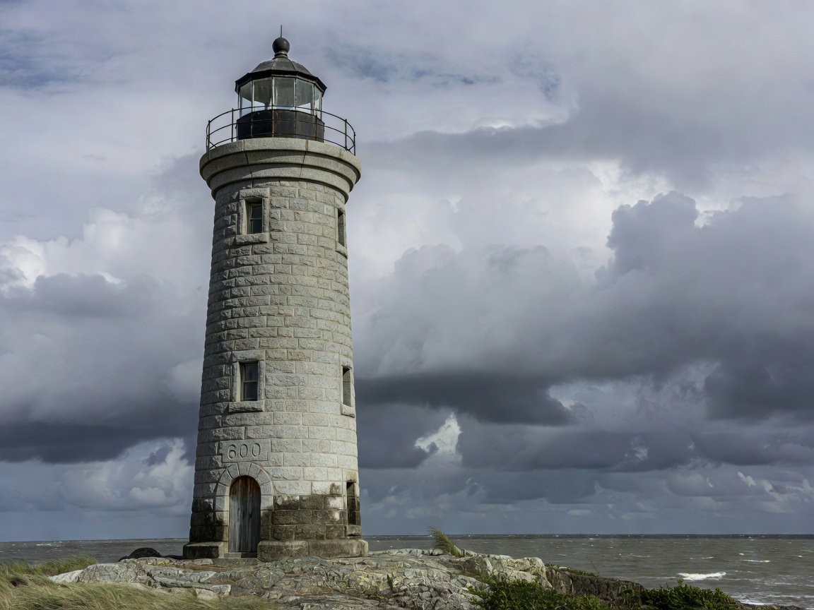 Exterior shot of a classic granite masonry lighthouse tower with lantern dome
